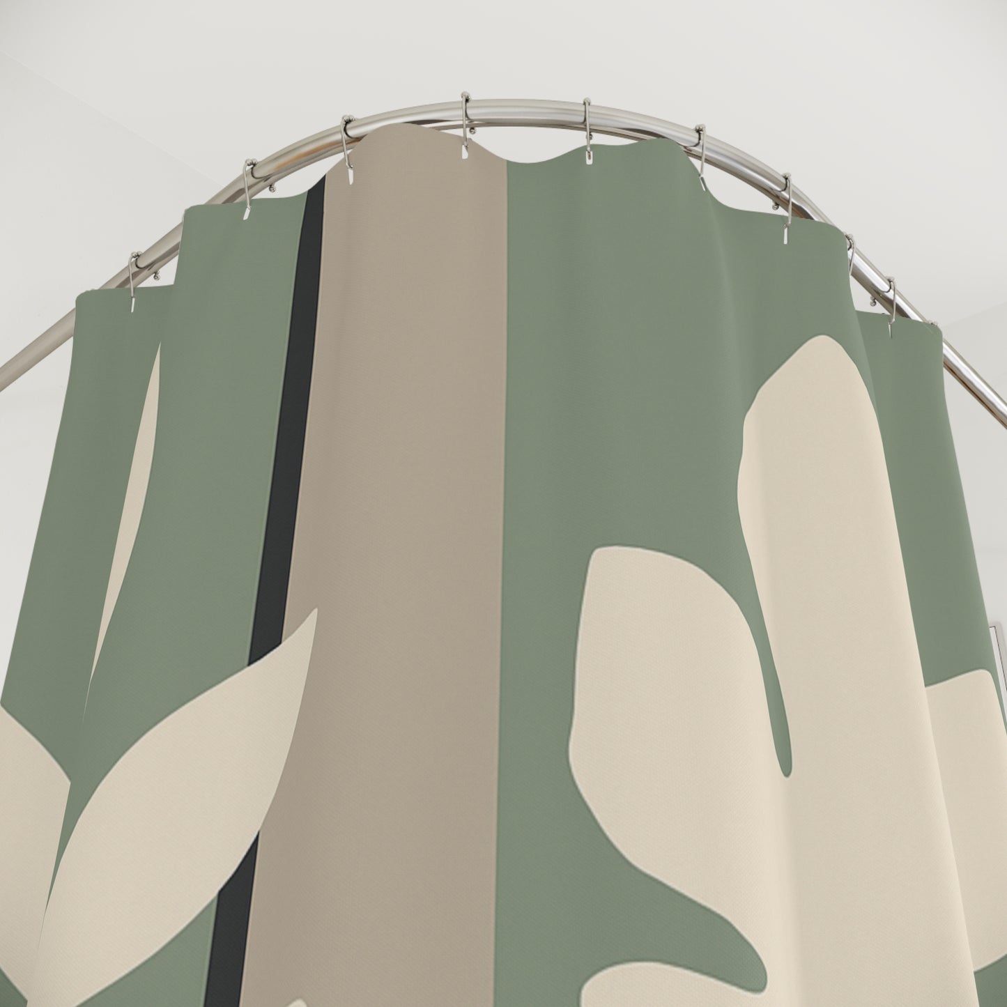 Shower curtain with green, beige, and white leaf pattern on a metal rod.