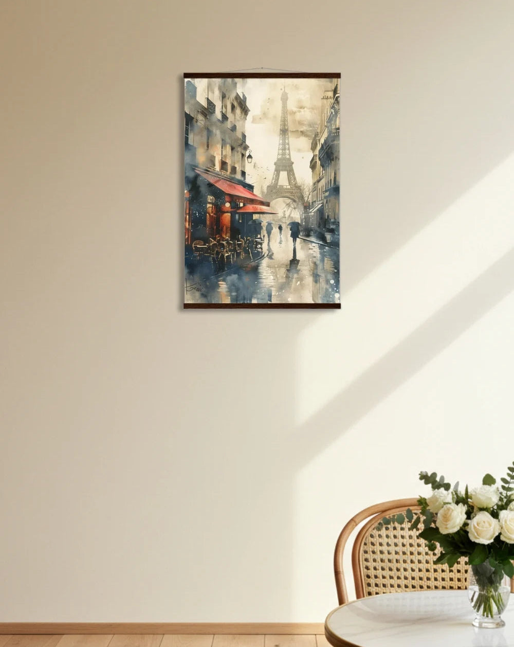 Framed artwork of a cityscape with Eiffel Tower on a wall above a table with flowers.
