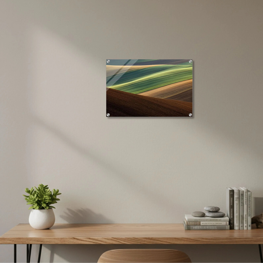 Art print of a landscape on a wall above a wooden desk with decor items.