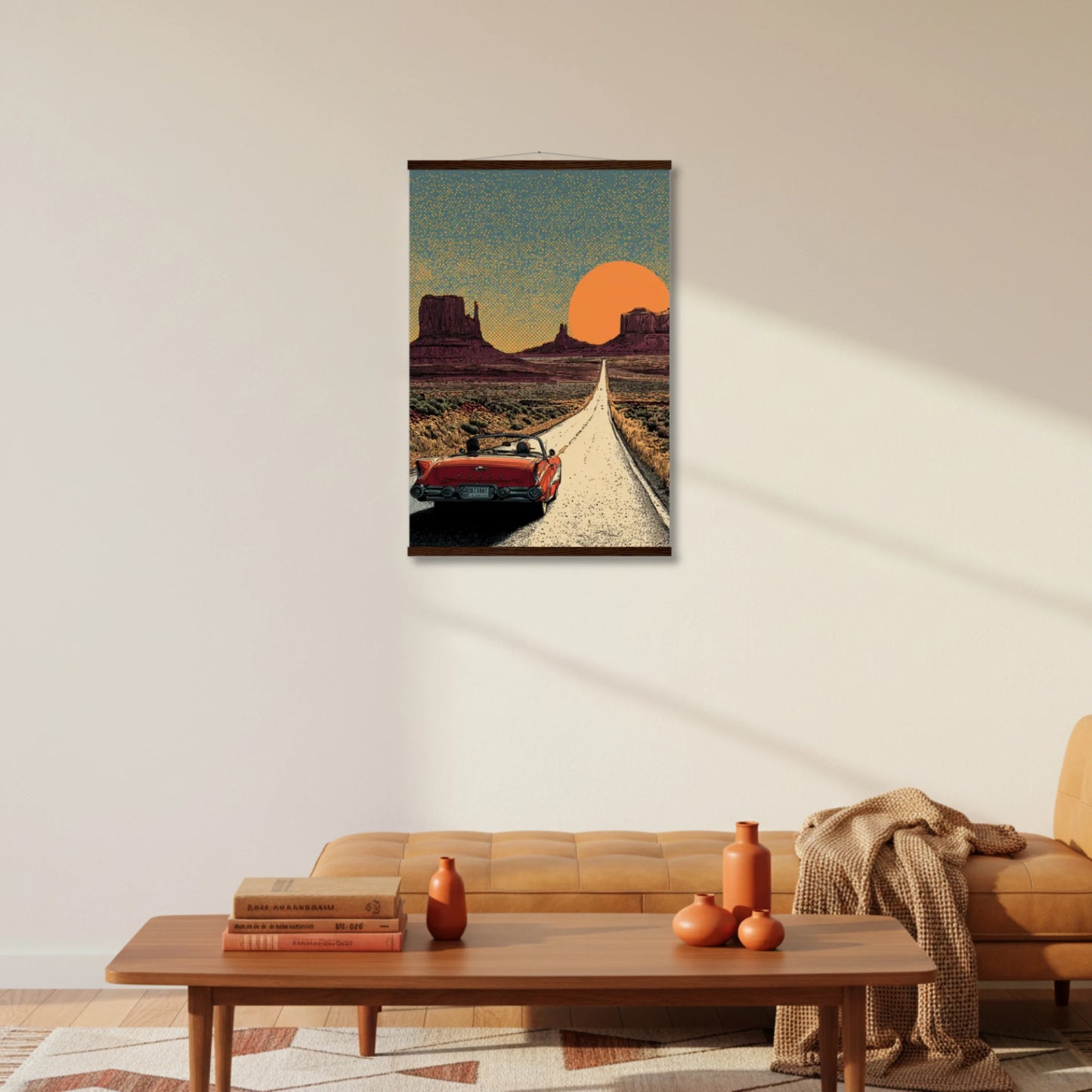 Framed artwork of a desert scene with a red car on a road, hanging above a living room sofa.