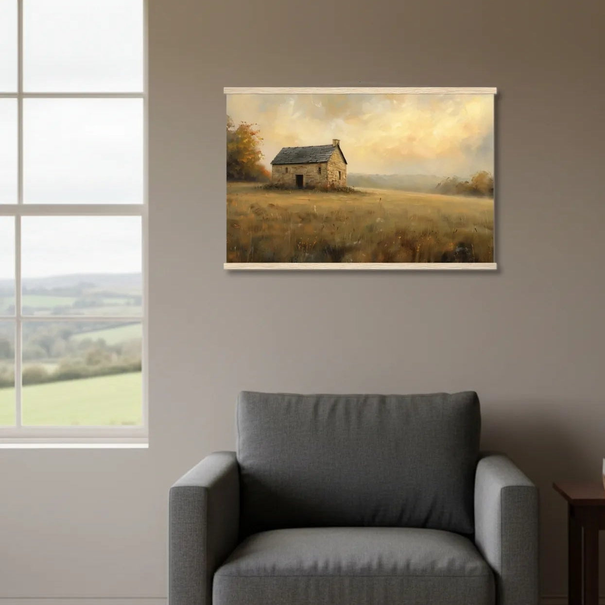 Gray armchair in a room with a painting of a field and house on the wall.